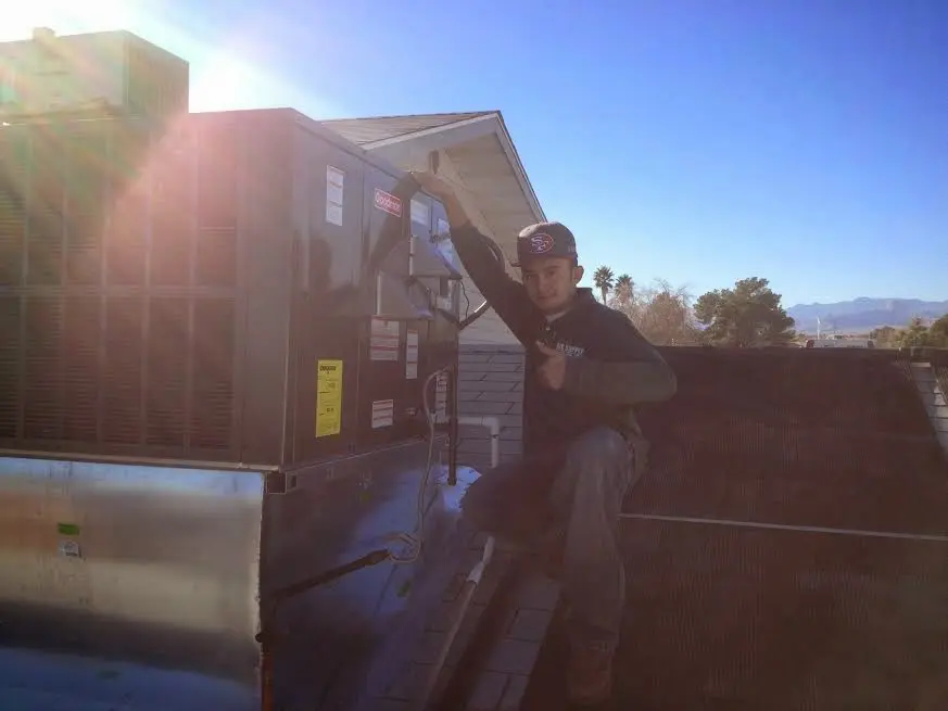 HVAC technician performing Air Duct Cleaning on a rooftop unit in Bastrop